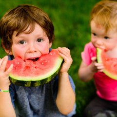 zwei Kinder essen Melone