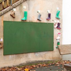 Wandtafel im Außenbereich mit Gummistiefeln an der Wand