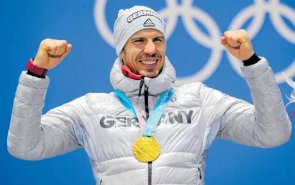 Aufnahme von Arndt Peiffer den Olympiasieger von 2018 im Biathlon. Er jubelt, hebt beide Beide nach oben und freut sich über seine Medaille.
