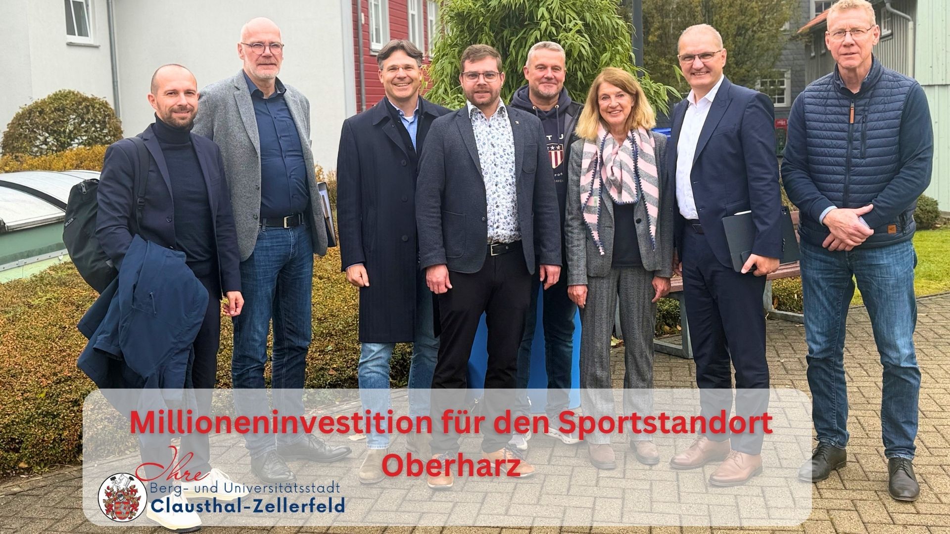 Meldungen 2026 (Facebook-Video) - 1 Gruppenfoto von sieben Männern und einer Frau im Freien. Die Personen stehen nebeneinander und blicken in die Kamera. Im unteren Bildbereich steht auf einer halbtransparenten Fläche der Schriftzug „Millioneninvestition für den Sportstandort Oberharz“ sowie das Logo der Berg- und Universitätsstadt Clausthal-Zellerfeld.