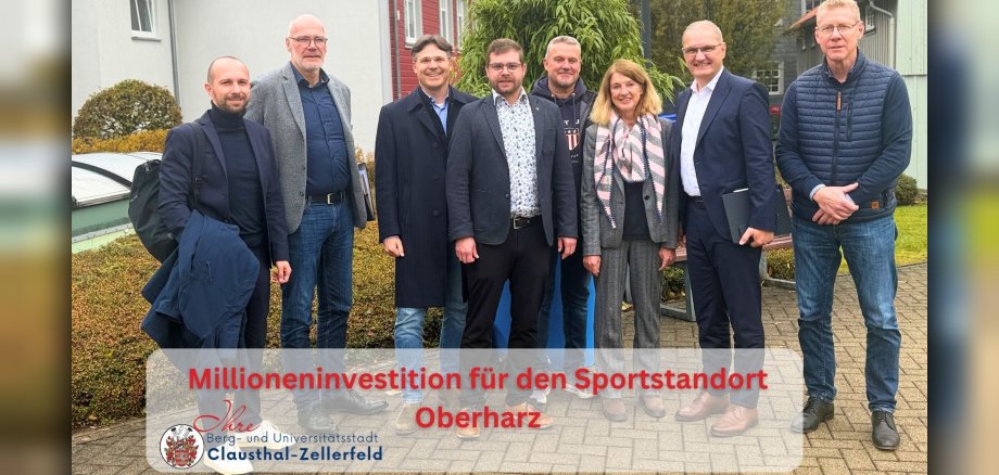 Meldungen 2026 (Facebook-Video) - 1 Gruppenfoto von sieben Männern und einer Frau im Freien. Die Personen stehen nebeneinander und blicken in die Kamera. Im unteren Bildbereich steht auf einer halbtransparenten Fläche der Schriftzug „Millioneninvestition für den Sportstandort Oberharz“ sowie das Logo der Berg- und Universitätsstadt Clausthal-Zellerfeld.