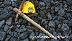 Niedersächsisches Bergarchiv Spitzhacke und Bergmannshelm liegend auf Steinen